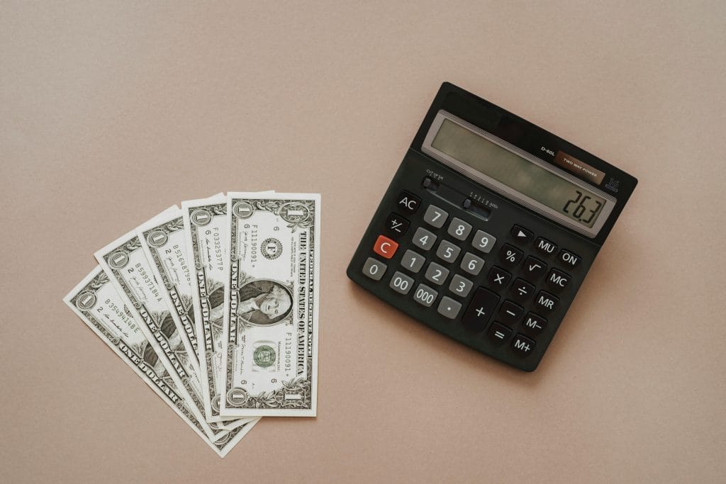 Dollar bills and calculator on beige desk for budgeting